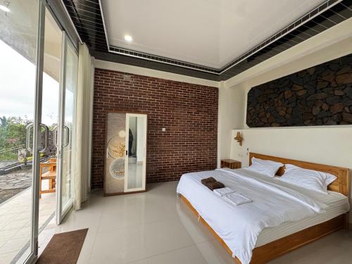 a bedroom with a large bed and a brick wall at Nona Lodge in Tetebatu