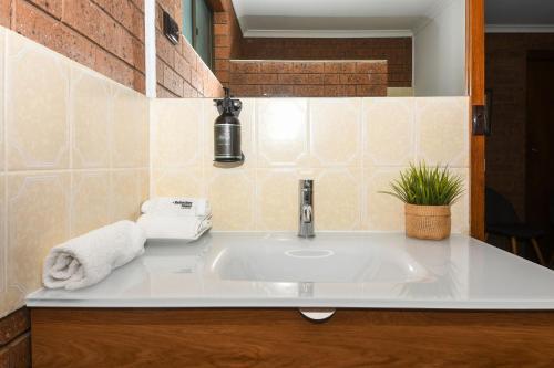 a white sink in a bathroom with a tile wall at Greenacres Motel in Corowa
