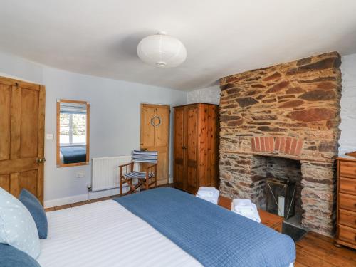 Schlafzimmer mit einem Bett und einem Steinkamin in der Unterkunft Armada Cottage in Dartmouth