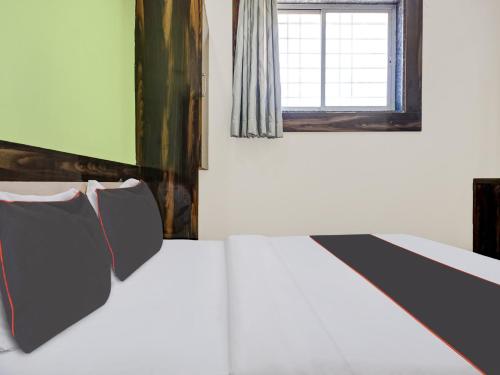 a bed with black and white pillows and a window at Hotel O Panchratna in Chakan