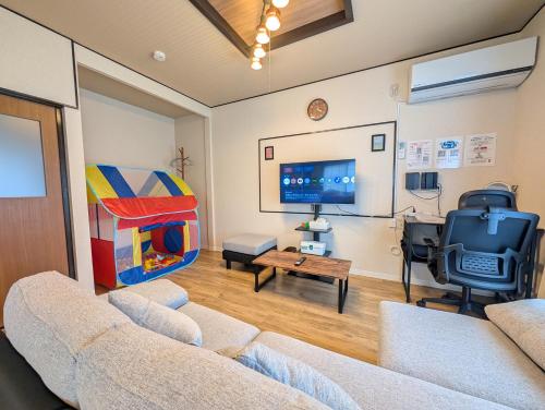 a living room with two couches and a tv at Nagoya Station is 17 minutes by car parking for 2 cars! Up to 11 people pets welcome! in Kiyosu