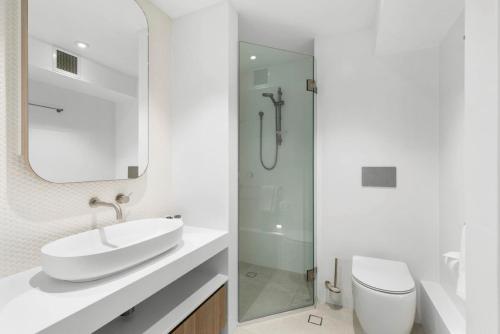 a white bathroom with a sink and a toilet at Fairshore in Noosa Heads