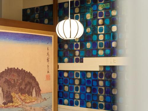 a chandelier hanging over a wall with a wall of glass at Retrospect Stay Yokohama in Yokohama