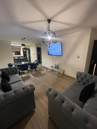 a living room with two couches and a flat screen tv at Departamentos Isla del Carmen in Culiacán