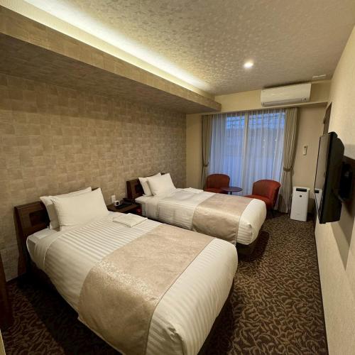 a hotel room with two beds and a television at HOTEL ARROWS Arashiyama in Kyoto