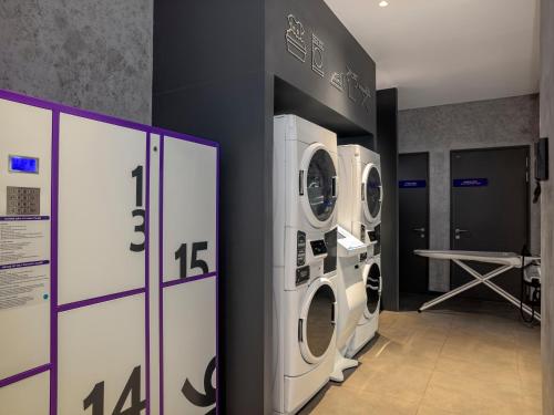 a laundry room with three washing machines on a wall at Tru by Hilton Da Nang City Centre in Da Nang