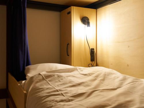 a bedroom with a bed and a light on a cabinet at Retrospect Stay Yokohama in Yokohama