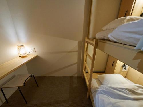 a room with two bunk beds and a desk with a lamp at Retrospect Stay Yokohama in Yokohama