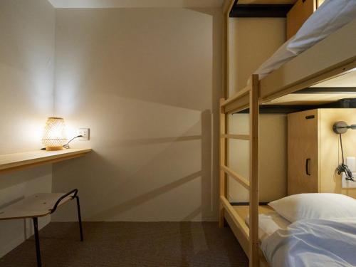 a bedroom with bunk beds with a desk and a lamp at Retrospect Stay Yokohama in Yokohama