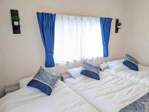 two beds in a room with blue curtains at Nagoya Station is 17 minutes by car parking for 2 cars! Up to 11 people pets welcome! in Kiyosu