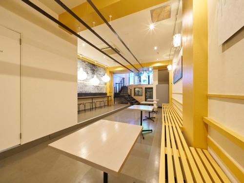 a room with yellow walls and a table and benches at Retrospect Stay Yokohama in Yokohama