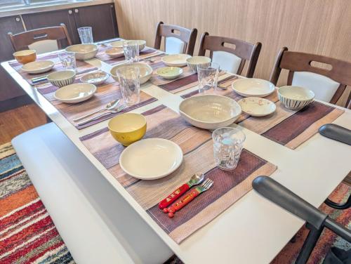 a table with plates and bowls and glasses on it at Nagoya Station is 17 minutes by car parking for 2 cars! Up to 11 people pets welcome! in Kiyosu