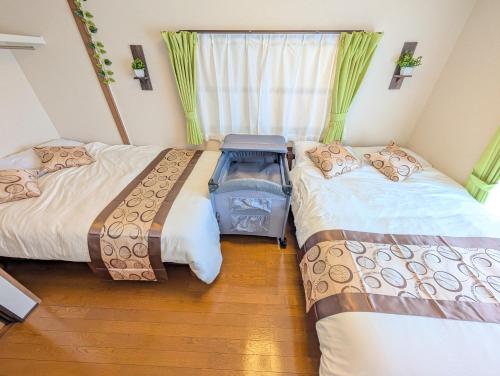 two beds in a room with a window at Nagoya Station is 17 minutes by car parking for 2 cars! Up to 11 people pets welcome! in Kiyosu
