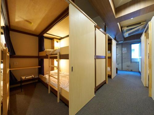 a dorm room with bunk beds and a hallway at Retrospect Stay Yokohama in Yokohama