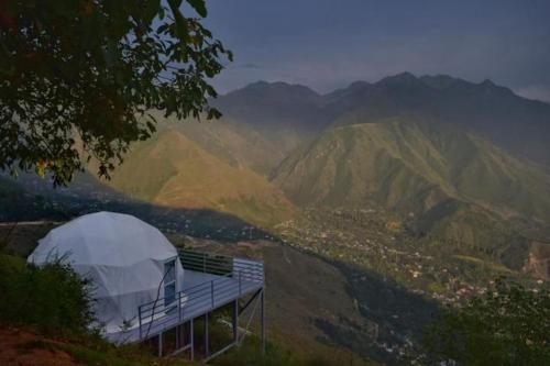 a tent on top of a hill with mountains at North Cliff Cafe & Retreat in Srinagar