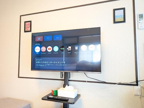 a flat screen tv on a stand in a room at Nagoya Station is 17 minutes by car parking for 2 cars! Up to 11 people pets welcome! in Kiyosu