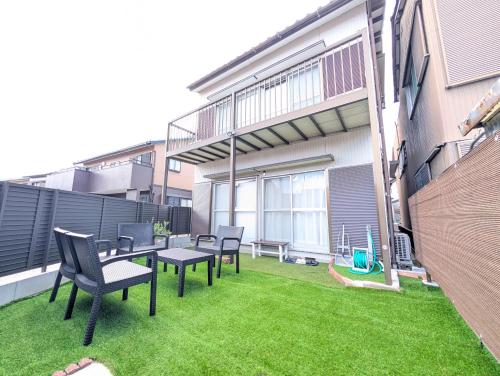 a small backyard with chairs and a table and grass at Nagoya Station is 17 minutes by car parking for 2 cars! Up to 11 people pets welcome! in Kiyosu