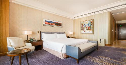 青島市にあるQingdao Star River Hotelのベッドとテーブルと椅子のあるホテルの部屋