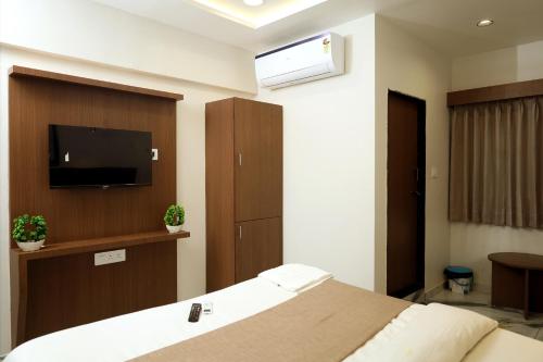 a bedroom with a bed with a flat screen tv at Hotel Sai, Naranpura in Ahmedabad