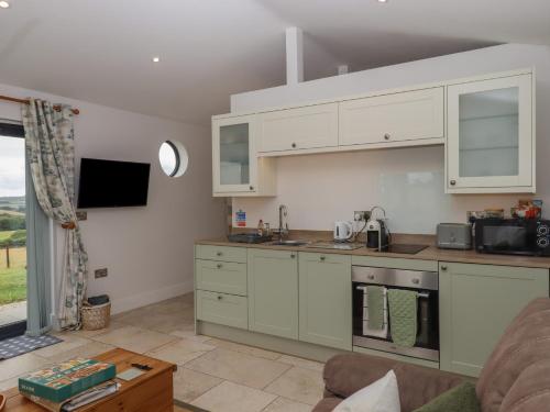 a kitchen with white cabinets and a couch in a room at The Pennymoor in Tiverton