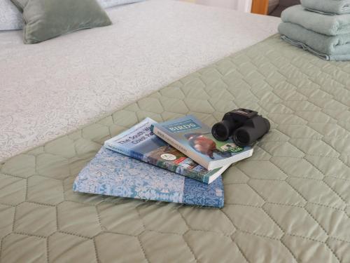 a pile of books and a camera on a bed at The Pennymoor in Tiverton