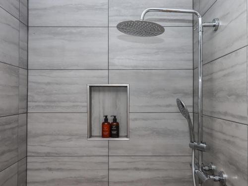a shower with a glass door with bottles on a shelf at The Pennymoor in Tiverton