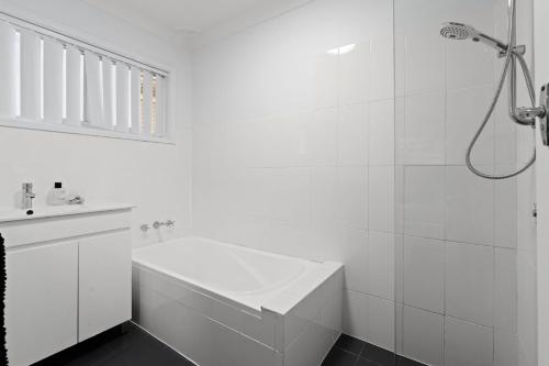 a white bathroom with a shower and a sink at Salt and Stone Modern Pearl Beach Stay 2 Mins to Ocean in Pearl Beach