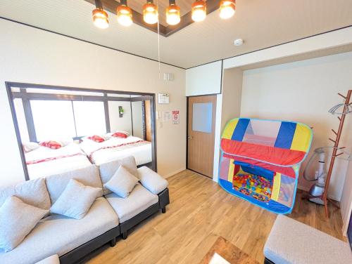 a room with a couch and a bed and a window at Nagoya Station is 17 minutes by car parking for 2 cars! Up to 11 people pets welcome! in Kiyosu