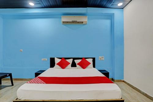 1 cama con almohadas rojas en una habitación azul en Hotel O Mayur Bulandshahr, en Bulandshahr