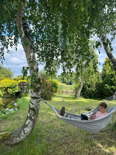 a woman sitting in a hammock under a tree at Apartamenty TUTERRA III in Zabagnie