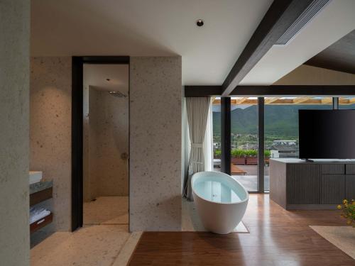ein großes Badezimmer mit Badewanne und Fernseher in der Unterkunft Sunny Aerie丨 Golden Peak Resort in Baisha