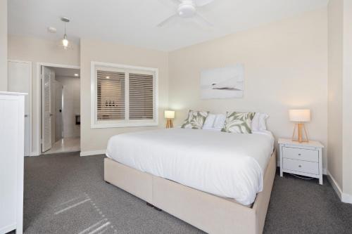 a white bedroom with a large bed and a window at Park View Apartment in Mantra Salt Resort by uHoliday - 2BR, 1BR and Hotel Room configurations available in Kingscliff