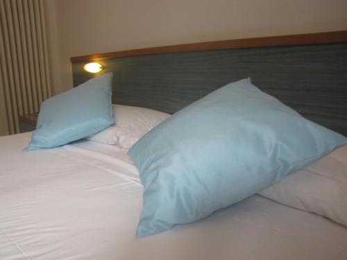 a bed with two blue pillows on top of it at Residence Villa Margherita in Brenzone sul Garda
