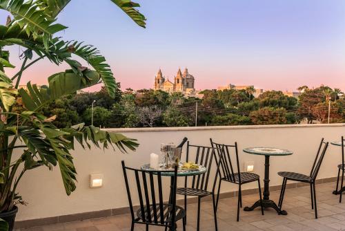 a table and chairs on a balcony with a view of a castle at Ta' Nina Boutique in Mdina