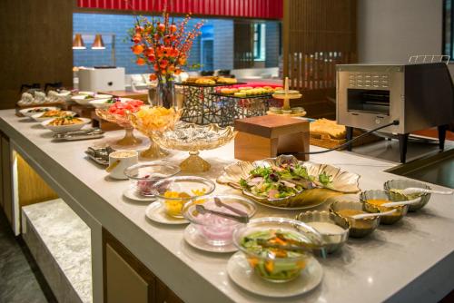 a buffet line with bowls and plates of food at Ease Hotel · Yi (Xi’an Bell and Drum Tower Xiaozhai Datang Everbright City) in Xi'an