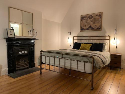 a bedroom with a bed with a fireplace and a mirror at Tranquil Victorian Villa with Hot Tub & Sauna in Colwyn Bay