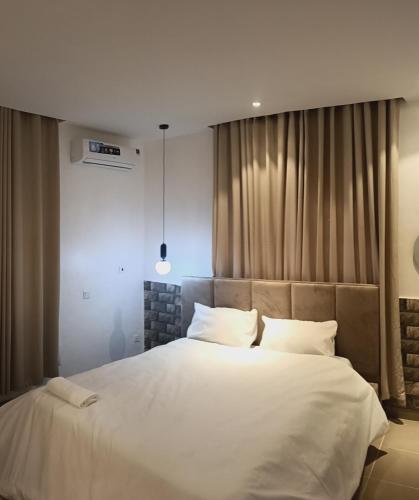 a bedroom with a large bed with white sheets and pillows at Delight Apartment in Ikeja
