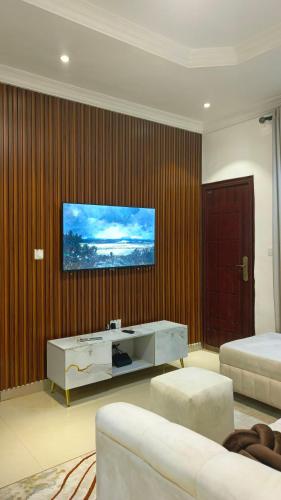 a living room with two beds and a television on a wall at Delight Apartment in Ikeja