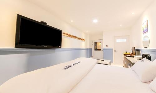 a bedroom with a large white bed and a flat screen tv at Hotel Yeogieutte Dongdaegu in Daegu