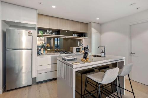 a kitchen with a refrigerator and two bar stools at Iconic Views - Queen's Wharf 1BR - Casino & South Bank in Brisbane