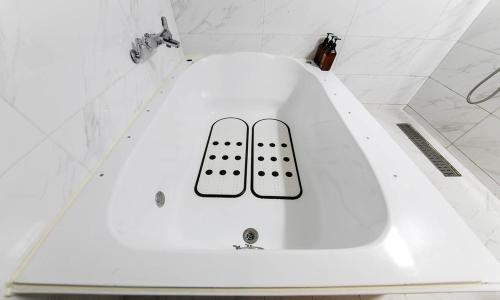 a white bath tub with two remote controls on it at Hotel Yeogieutte Dongdaegu in Daegu