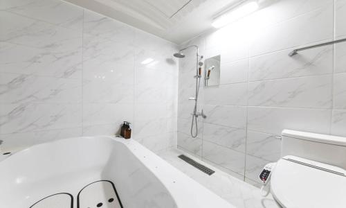 a white bathroom with a tub and a toilet at Hotel Yeogieutte Dongdaegu in Daegu
