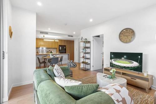 a living room with a green couch and a kitchen at Modern 2BR near The Gabba & BBQ in Brisbane
