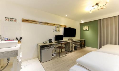 a bedroom with a bed and a desk with a television at Hotel Yeogieutte Dongdaegu in Daegu
