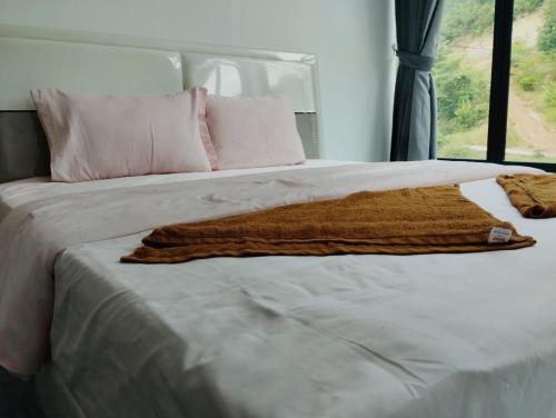 a bed with a brown blanket on it with a window at Waterfall Guesthouse1 in Phumĭ Kaôh Rŏng