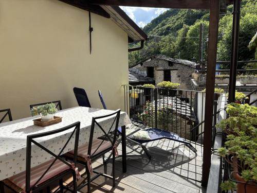a patio with a table and chairs on a balcony at Casetta immersa nella natura in Ostana