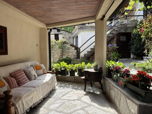 a patio with a couch and some potted plants at Casetta immersa nella natura in Ostana