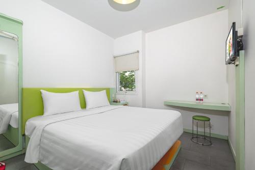a bedroom with a large white bed and a desk at Swift Inn Aeropolis Airport in Tangerang