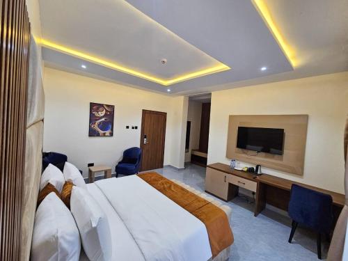 a hotel room with a large bed and a television at Reens Suites and Apartments in Port Harcourt