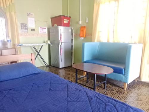a room with a blue chair and a table and a refrigerator at Roomstay Nina Marang Pulau Kapas in Marang